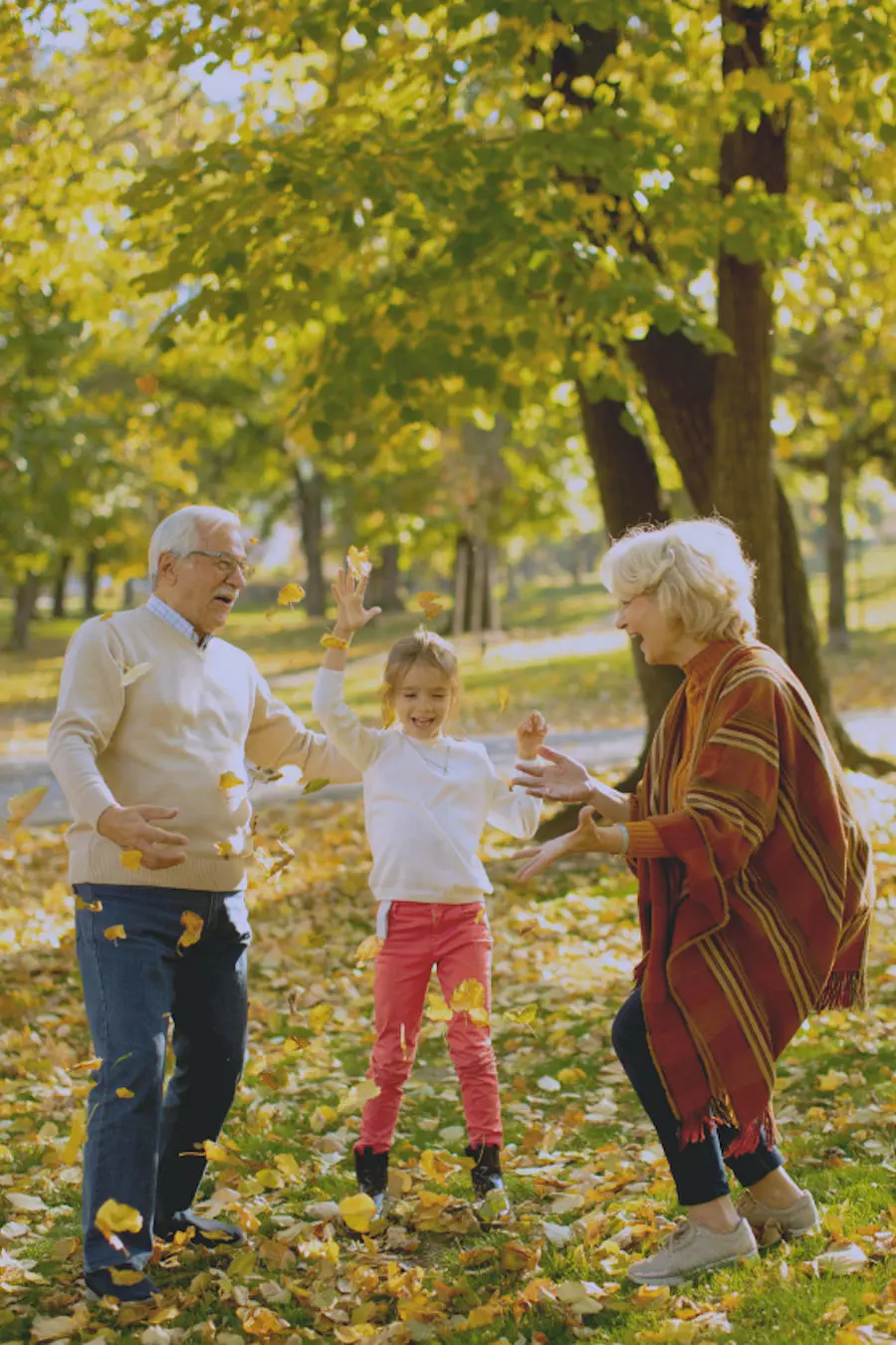 Grandparents playing with child in leaves